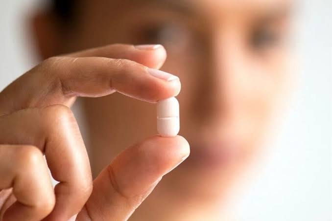 Mão segurando uma cápsula, representando a reposição hormonal com acompanhamento médico